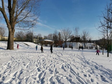 dzieci biegają po zaśnieżonym boisku