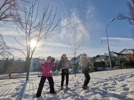 trójka dzieci rzuca śniegiem