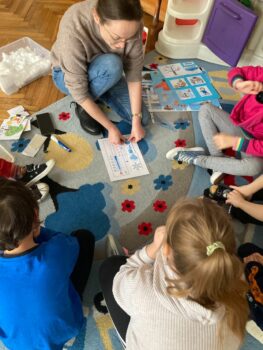 nauczycielka i dzieci układają pomoce na dywanie