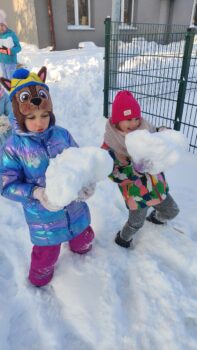 dwoje dzieci dźwiga spore kule śnieżne