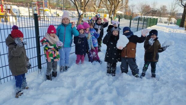 grupka dzieci radośnie pozuje do zdjęcia podczas zimowych zabaw