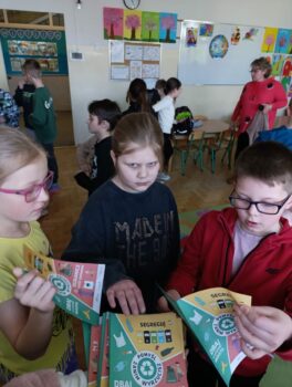 Dzieci czytają ulotki na temat zbierania i segregowania odpadów